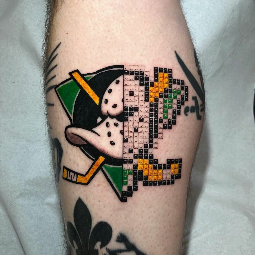 Tattoo combining two styles: half vintage hockey mask, half pixelated design, by Mat Rule.