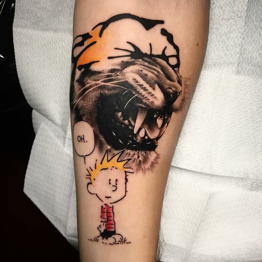 Tattoo featuring a roaring lion and a cartoon boy, blending two different styles by artist Mat Rule.