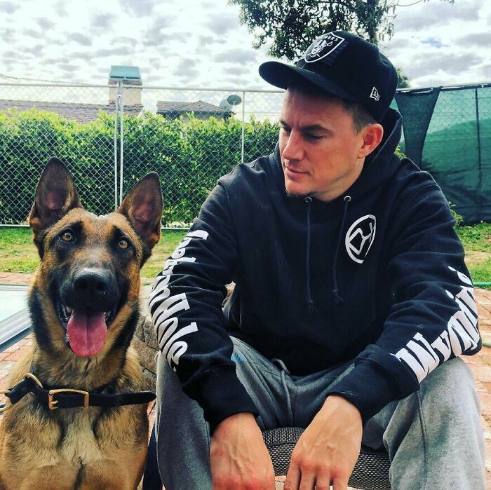 Celebrity sitting outdoors with a happy German Shepherd dog, showing love for dogs in a casual setting.