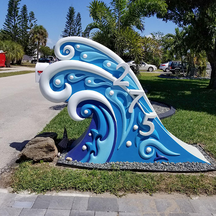 Creative and cool mailbox shaped like a blue ocean wave with house number 275 in a sunny neighborhood setting