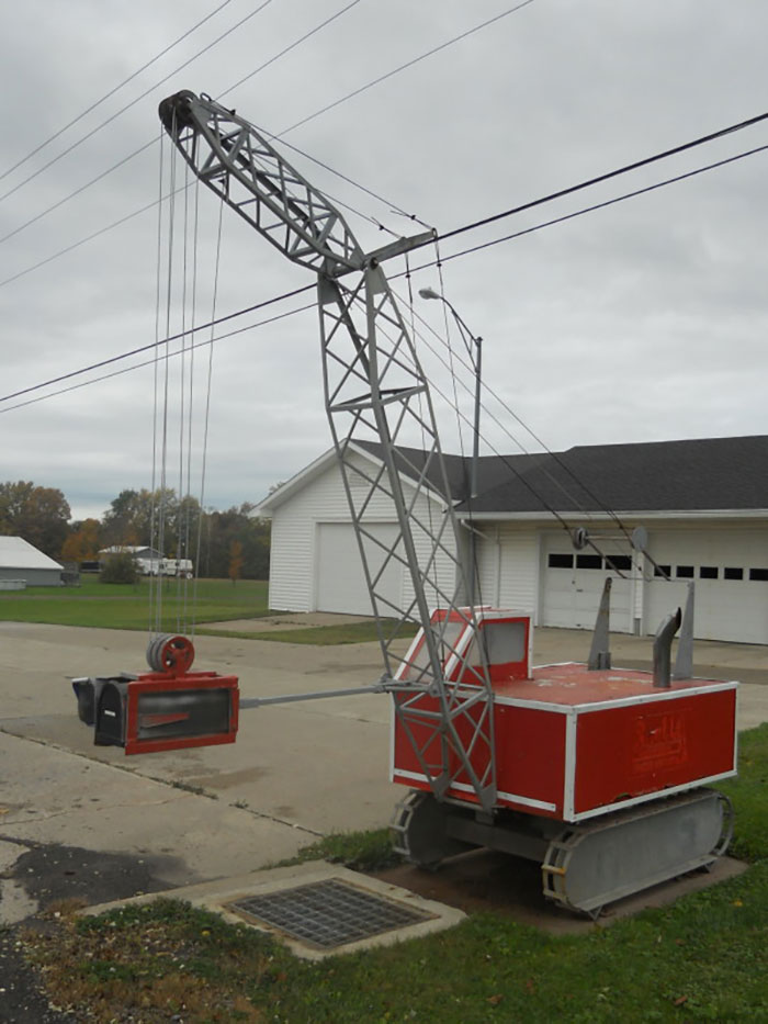 Creative and cool mailbox designed like a miniature construction crane with a suspended mail slot in a residential driveway.