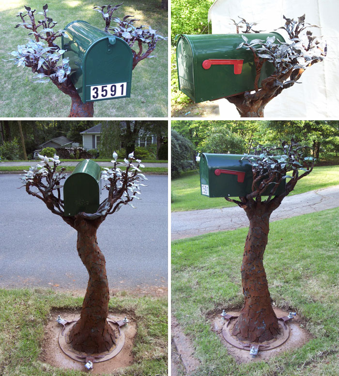 Creative mailbox designed as a tree with metal branches and leaves holding a green mailbox in a suburban setting.