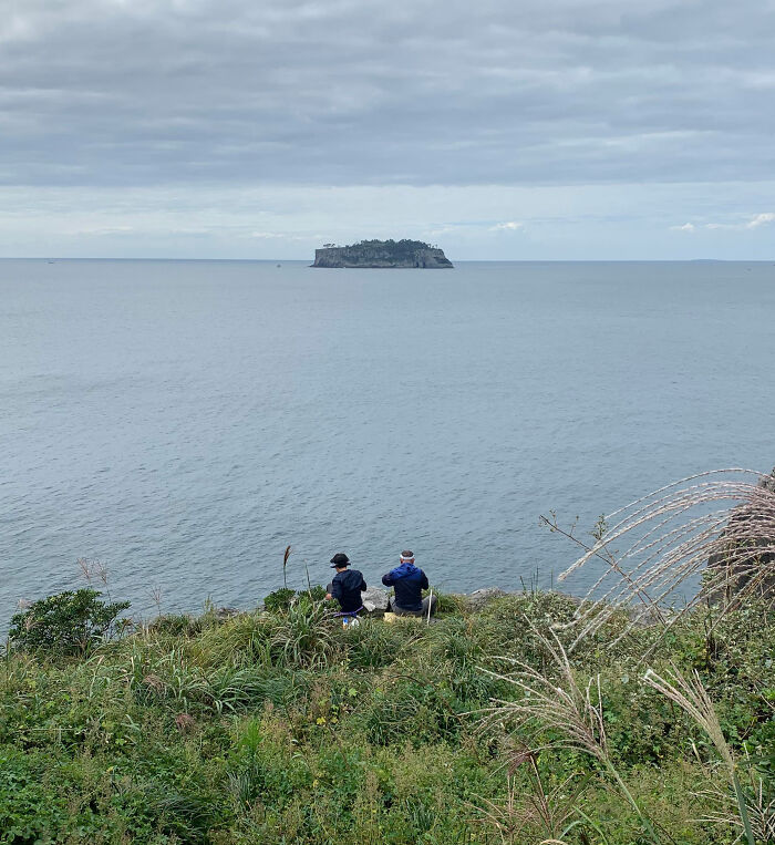 Old Korean Couple Hopped A Fence To Sit On The Edge Of A Cliff Eating Lunch Together And Fishing On Jeju Island. So Simple And So Sweet