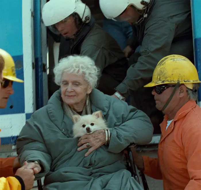 an old woman with a white Pomeranian dog saved by rescuers