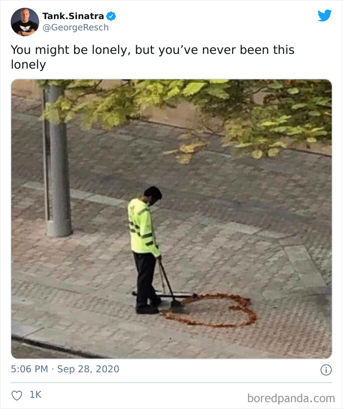 Man in high-visibility jacket sweeping leaves into a heart shape on the pavement, depicting single life humor.