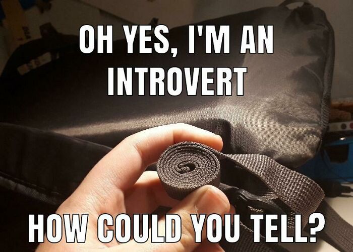 Hand holding a tightly rolled-up strap with text about being an introvert, illustrating funny introvert memes.