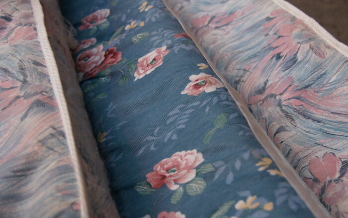 Close-up of vintage floral fabric patterns on folded cushions, illustrating textures for conspiracy theories discussion.