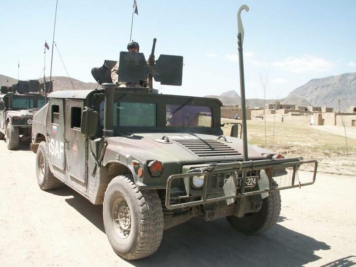 Military vehicle with soldier on top driving through a desert area, illustrating conspiracy theories people believe in.