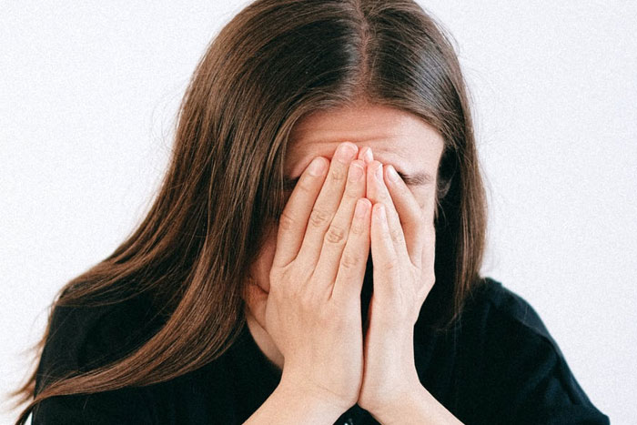 stressed woman covering her face with her hands