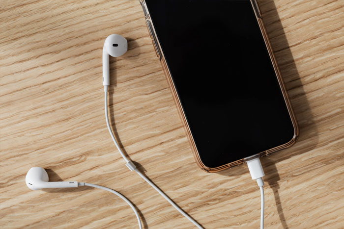 white earphones plugged into a smartphone