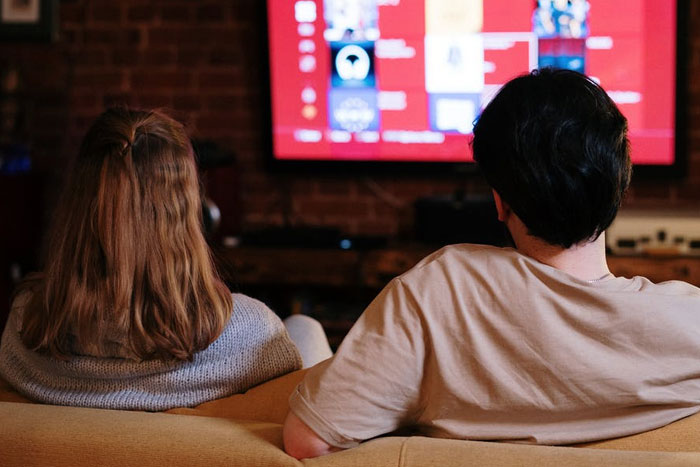 couple sitting on a couch, watching TV