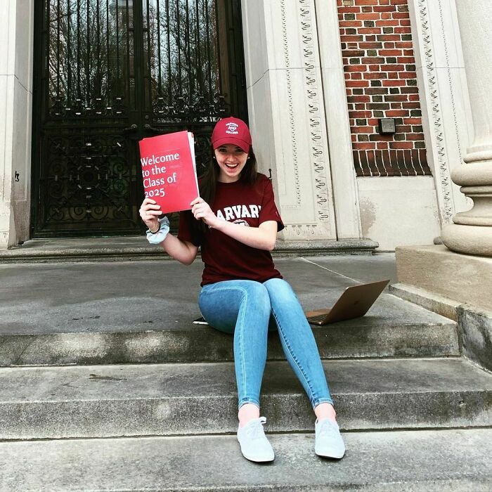 Abigail Mack wearing Harvard T-shirts and hat and holding Harvard papers Abigail Mack wearing Harvard T-shirts and hat and holding Harvard papers