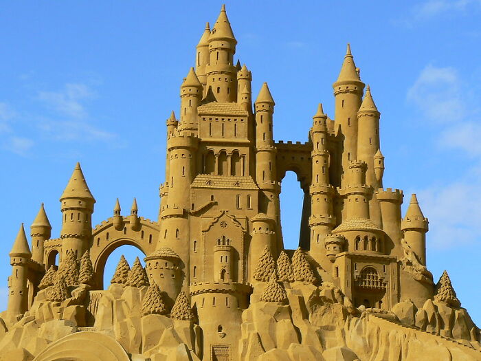 Intricate sandcastle with multiple towers and arches under a clear blue sky illustrating weird laws from around the world.
