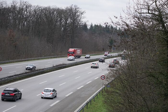 Highway scene with cars and trucks traveling under speed limit signs, representing weird laws from around the world.