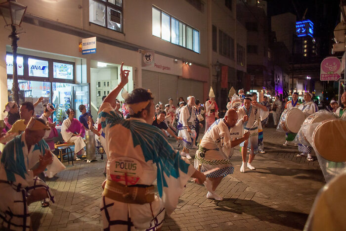 Group of people in traditional attire dancing and playing drums on a city street, illustrating weird laws from around the world.