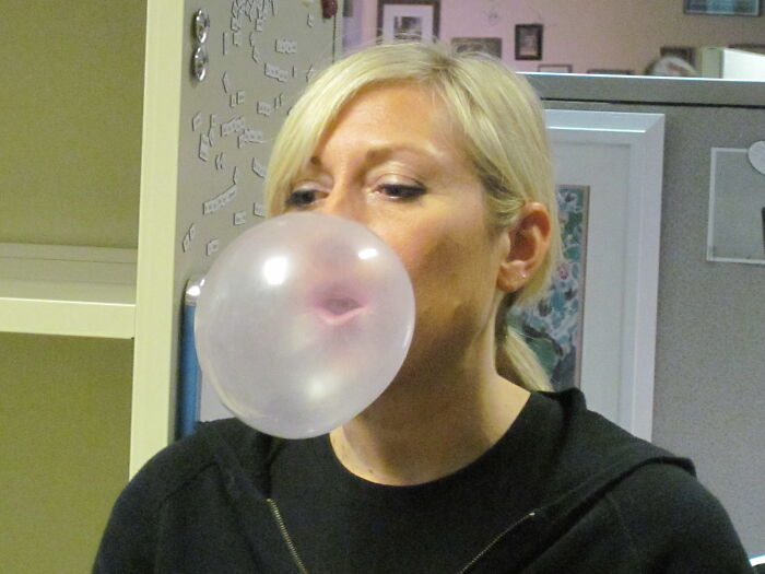 Woman blowing a bubble with chewing gum illustrating weird laws from around the world that sound made up but are true.