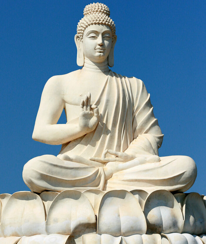 Large white Buddha statue sitting in lotus position against clear blue sky, illustrating weird laws from around the world