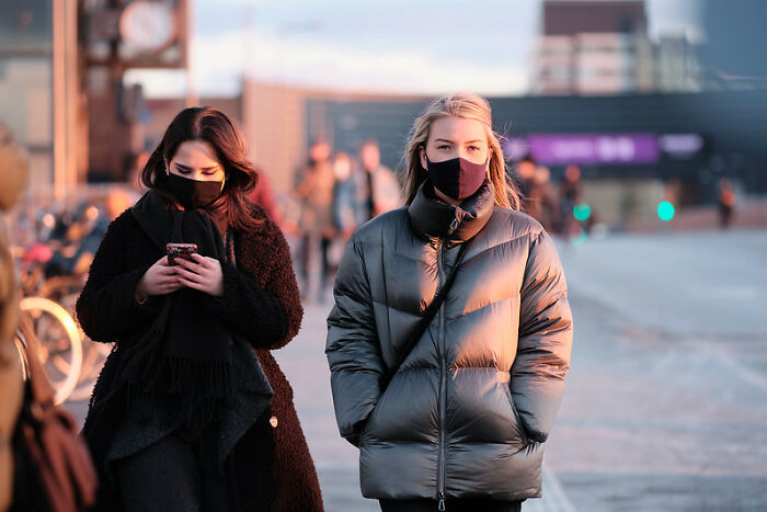 Two women wearing masks walk outdoors during sunset, illustrating awareness of weird laws from around the world.
