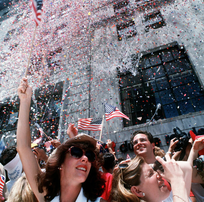 Crowd celebrating with American flags and confetti outdoors illustrating weird laws from around the world.