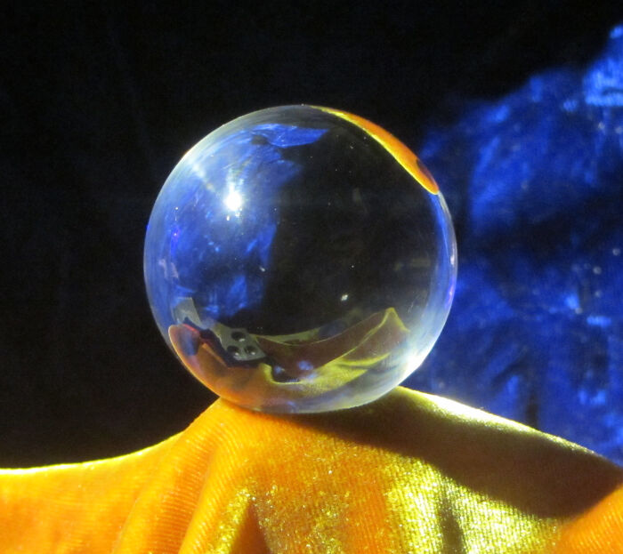 Clear glass sphere balancing on a bright yellow cloth with a dark blue background, illustrating weird laws from around the world.
