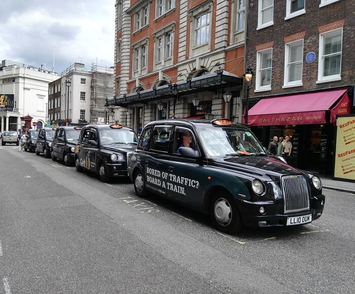 Black London taxis lined up on a city street, illustrating weird laws from around the world about transportation and traffic.