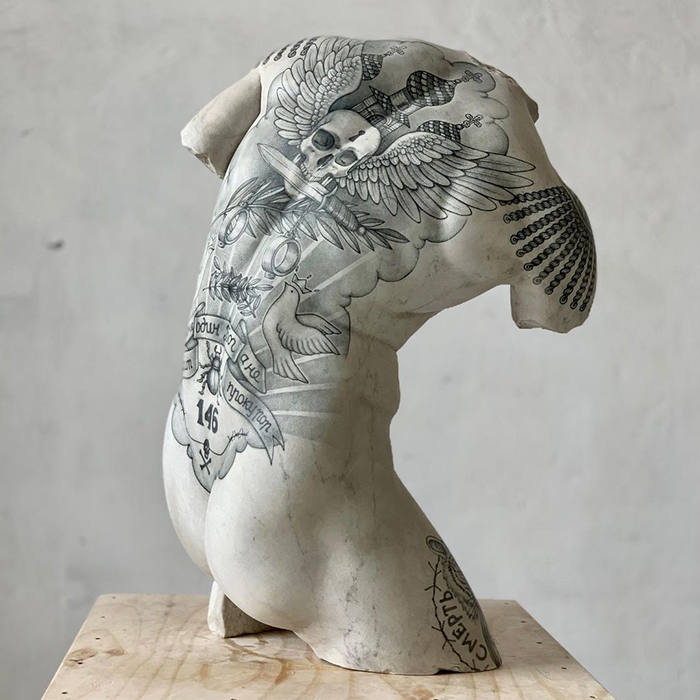 Tattooed sculpture by Italian artist featuring intricate designs on a classical bust.