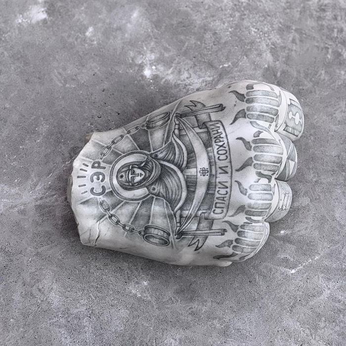 Tattooed sculpture by Italian artist featuring intricate designs on a clenched fist, showcasing unique artistic expression.