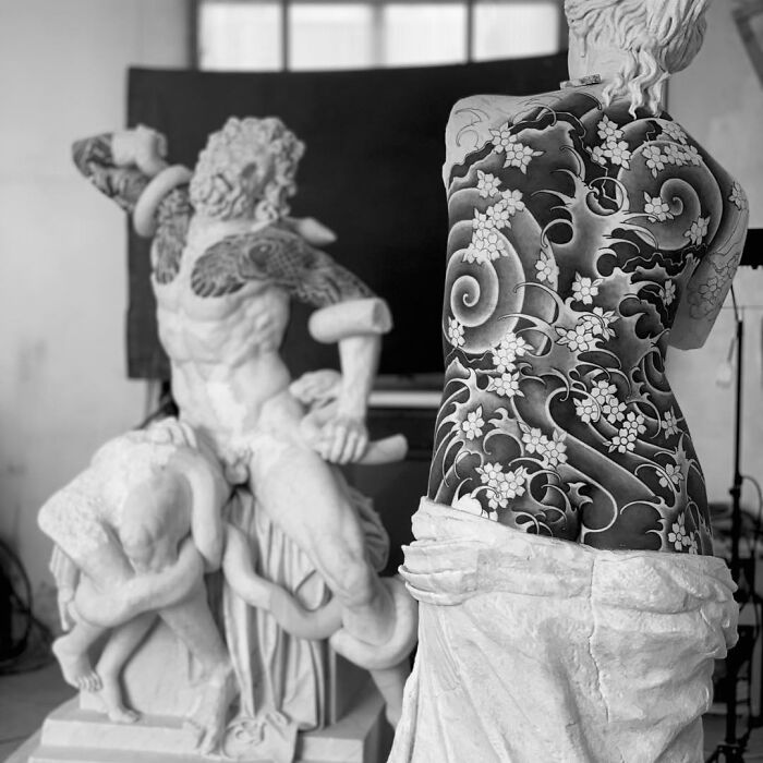 Sculptures adorned with intricate tattoo designs in an art studio setting.