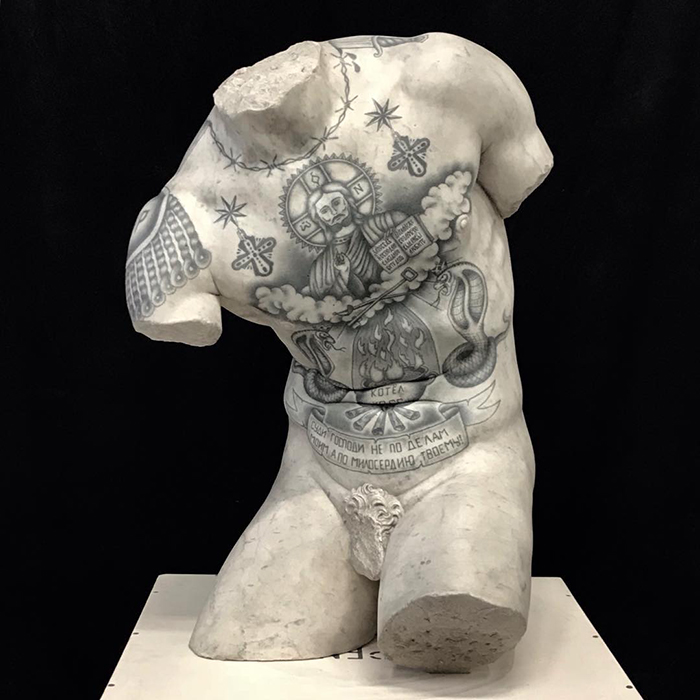 Tattooed sculpture by Italian artist showcases intricate designs on a classic marble torso.
