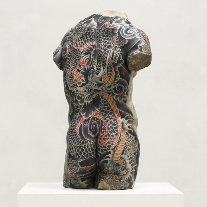Sculpture with intricate tattoo design by Italian artist on display.