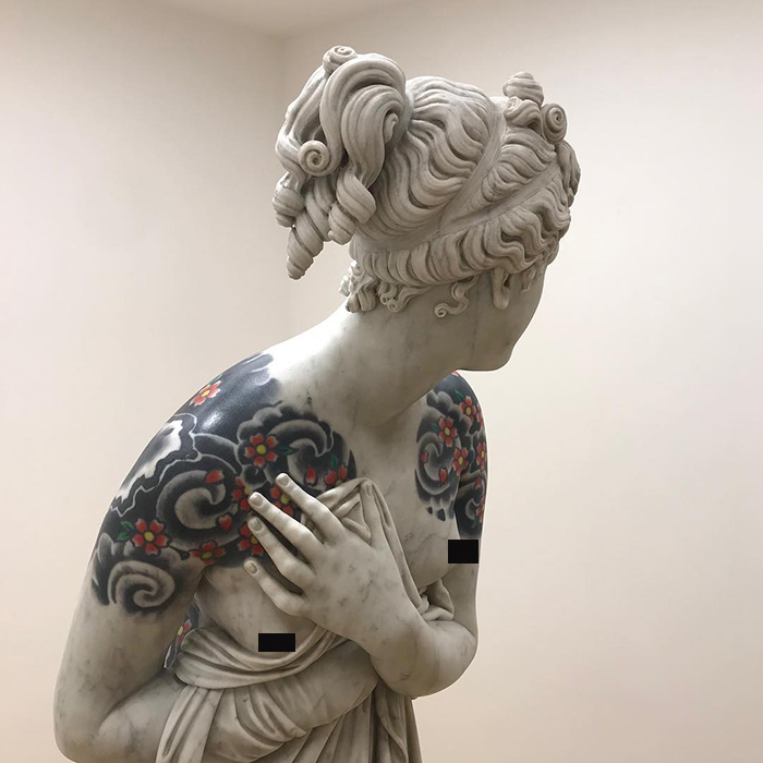 Italian artist adorns sculpture with colorful tattoos on its shoulders, showcasing art beyond skin.