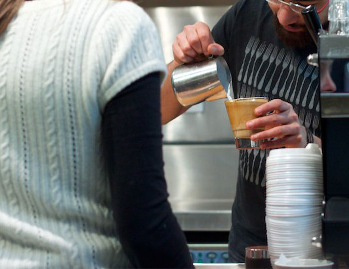 Barista pouring coffee foam into a glass cup, illustrating specific little things that are so irritating in daily life.