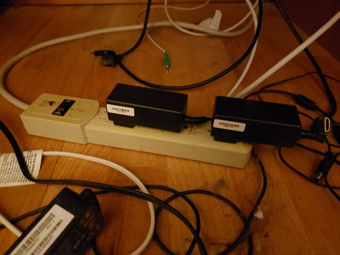 Tangled and cluttered power strip with multiple adapters and cables causing an irritating mess people can’t stand.