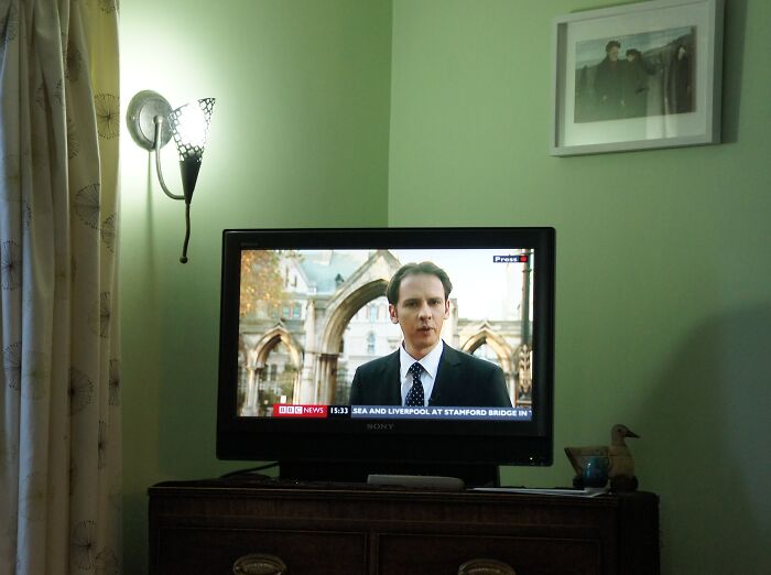 TV screen showing a news reporter indoors with soft lighting and simple decor, illustrating irritating little things.