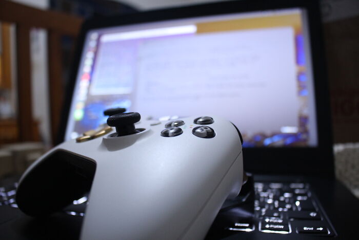 White gaming controller resting on a laptop keyboard, illustrating specific little things that are so irritating.