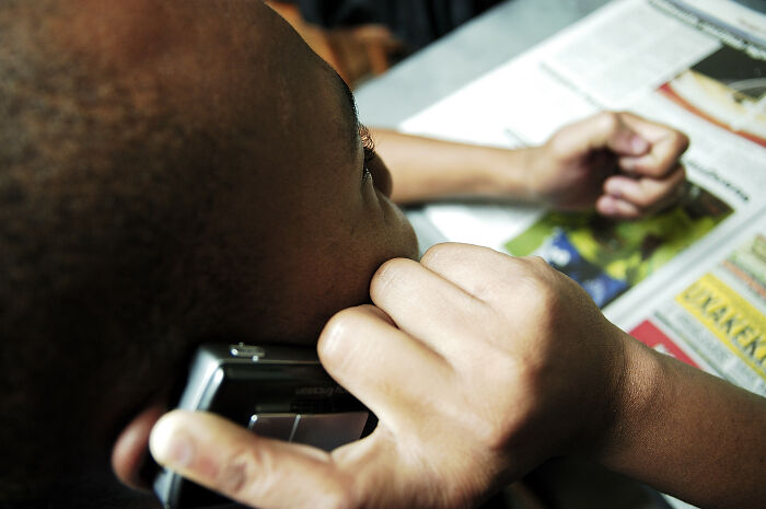 Person on phone covering ear with hand, highlighting one of the specific little things that are irritating to people.