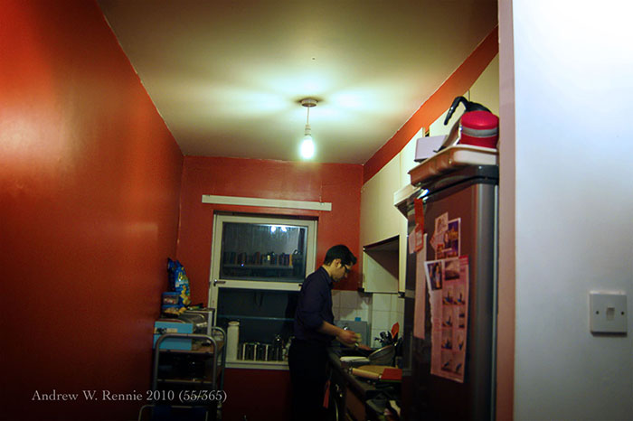 Person washing dishes in a small kitchen with red walls, illustrating specific little things that are irritating at home.