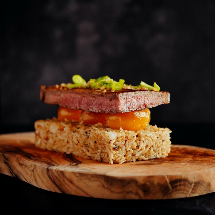 Adobo Fried Rice, Confit Egg Yolks, Pan Seared 28 Day Matured Rib Eye Marinated In Soy Sauce, Calamansi And Mirin, Garnished With Spring Onions And Fried Garlic Aka Tapsilog