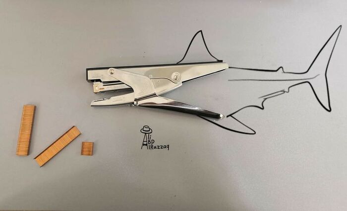 Stapler and staples creatively used in an interactive illustration resembling a shark, showcasing everyday items in art.