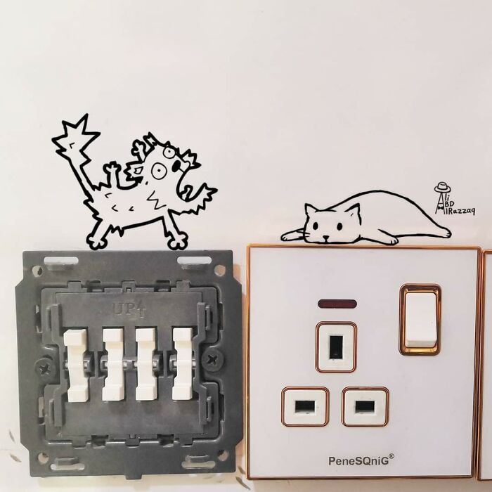 Interactive illustrations of cats creatively integrated with electrical switches and sockets on a white wall using everyday items.