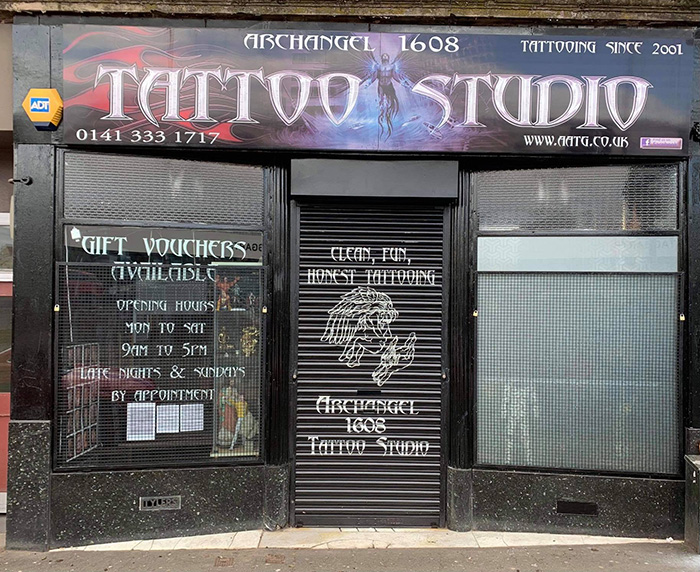 Exterior view of tattoo parlor Archangel 1608 with signage promoting honest tattooing services and gift vouchers. Exterior view of tattoo parlor Archangel 1608 with signage promoting honest tattooing services and gift vouchers.