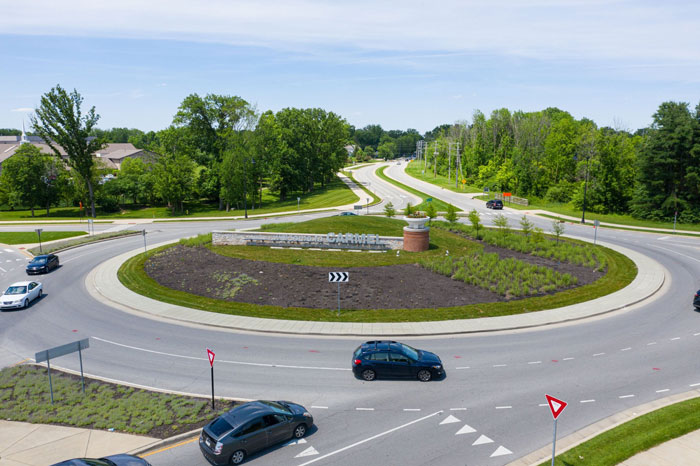A roundabout with several cars driving, surrounded by green trees and landscaped grass, illustrating interesting facts.