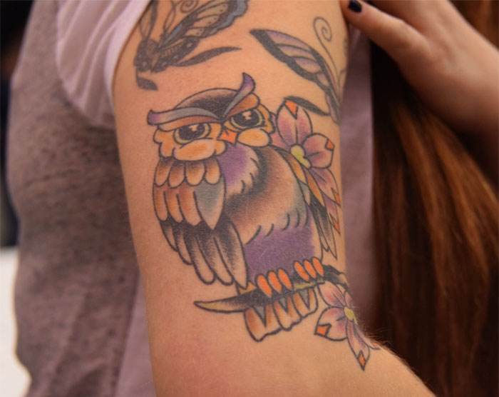 Colorful owl tattoo with flowers on arm, showcasing tattoo artistry for first-time clients.