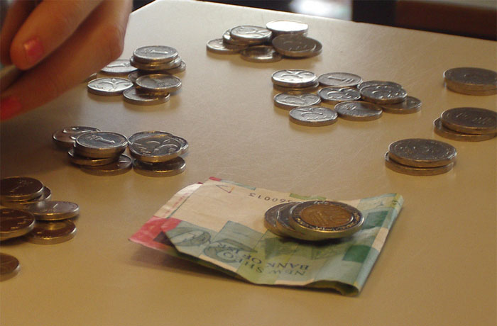 Coins and a small pile of banknotes on a table, representing payment scenarios shared by tattoo artists with new clients.