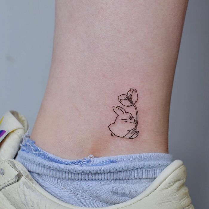 Small bunny tattoo on ankle of tattoo virgin, wearing sneaker.