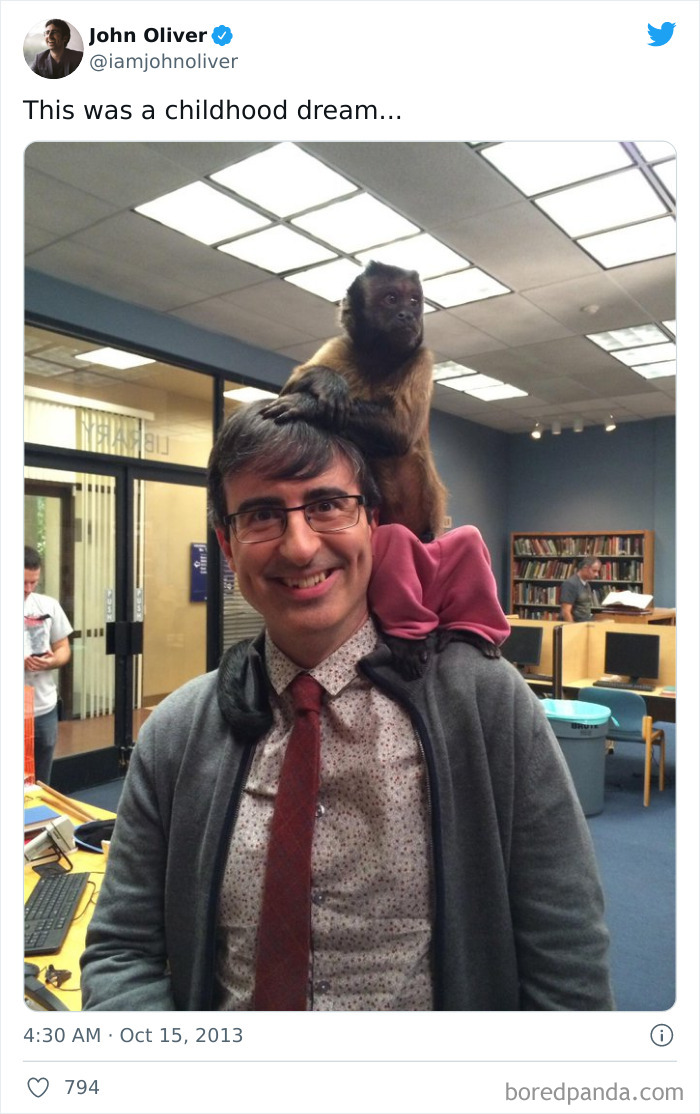 Man smiling with a monkey sitting on his head inside a library.