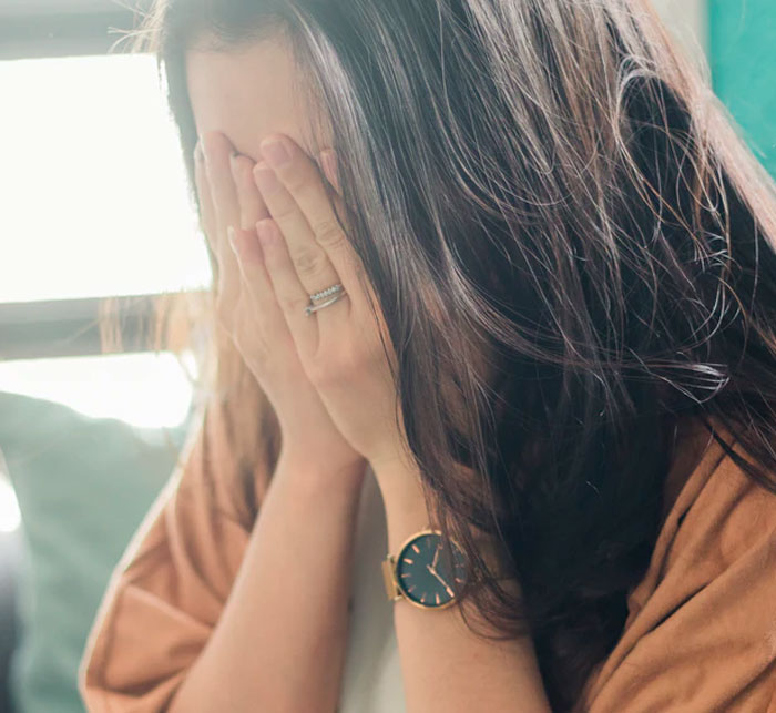 Woman covering her face with hands, reflecting on spot-on therapy questions that made everything click during a session