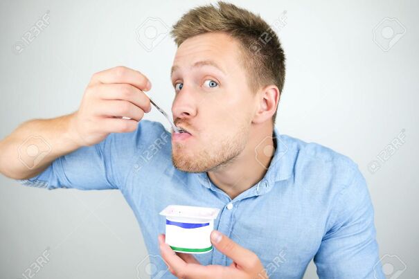 129189107-young-handsome-man-putting-spoon-with-yogurt-in-his-mouth-on-isolated-white-background.jpg