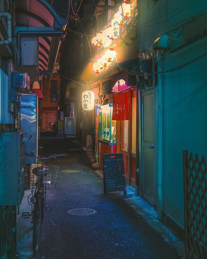 Narrow Japanese alley at night with glowing lanterns, small restaurants, and bicycles capturing the beauty of Japan.