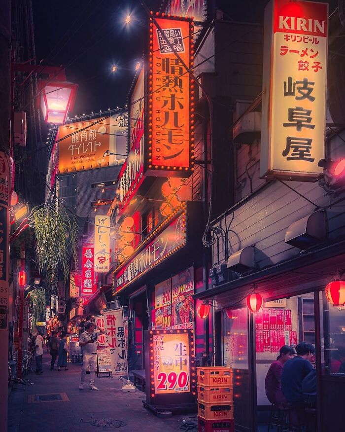 Night street scene in Japan with vibrant neon signs and people dining outdoors, capturing the beauty of Japan.